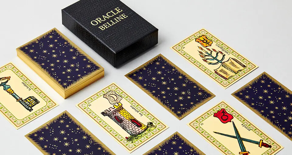 Oráculo de Belline: caja negra rotulada Oracle Belline, reversos estrellados y cartas con una torre, una llave y espadas