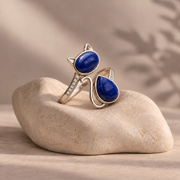 Caesia, bague chat en lapis lazuli posée, tête ovale aux oreilles pointues et corps en goutte avec sa queue.