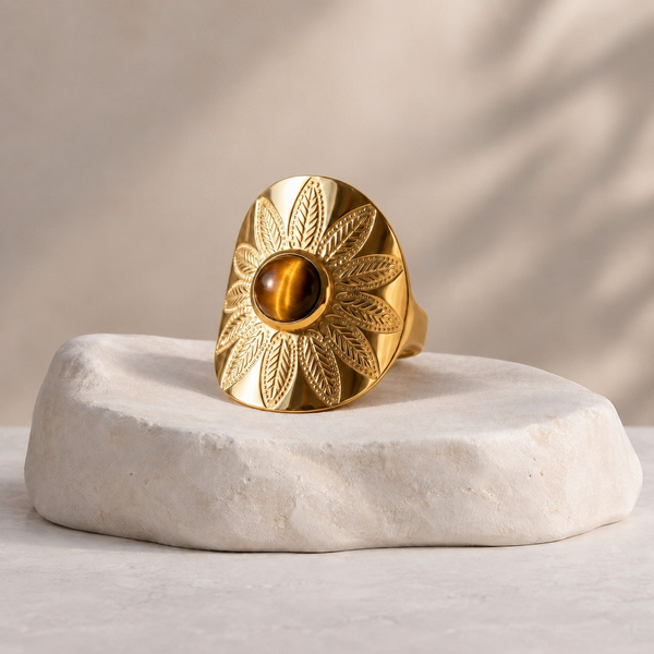 Grapte, bague mandala en œil de tigre posée, plateau ovale gravé d’une fleur et pierre ronde en son milieu.