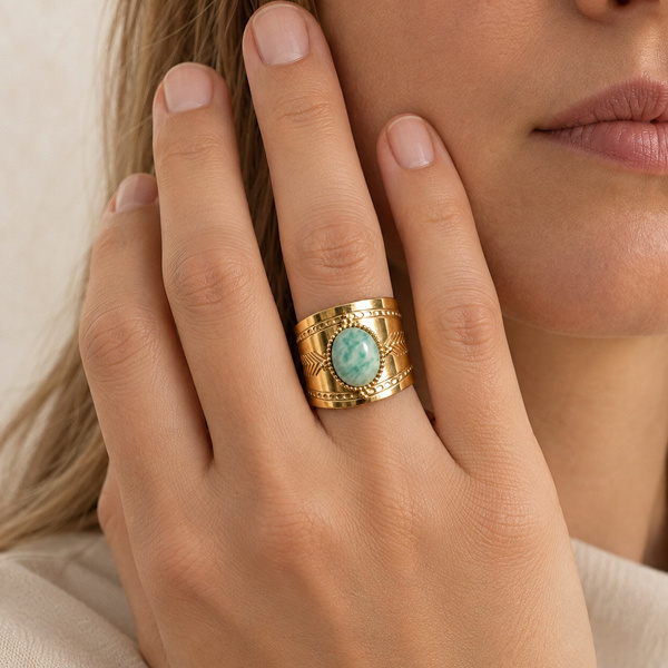 Bague large en amazonite portée, la main posée contre la joue.