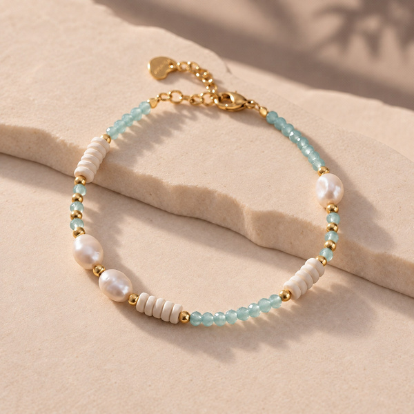 Bracelet en perles d’eau douce et perles bleues posé à plat, avec sa rallonge et son petit cœur.