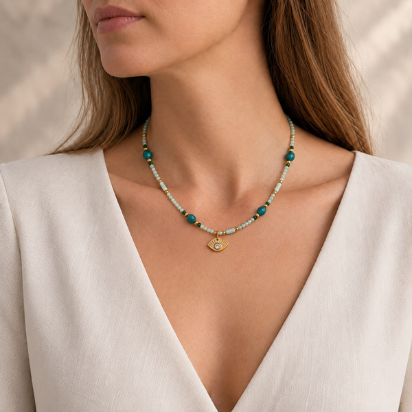 Collier œil en amazonite et apatite porté, l’œil doré entre les clavicules.
