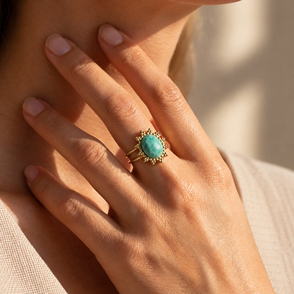 Bague fleur en amazonite portée, les doigts posés contre le cou.