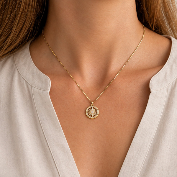 Collier soleil en zircon porté sous le cou, la médaille ronde au milieu du décolleté.