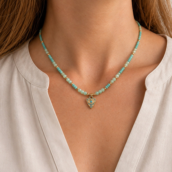 Collier œil en amazonite porté à la base du cou, le triangle doré entre les clavicules.