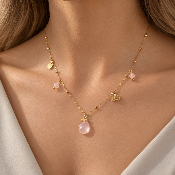 Collier couronne en quartz rose porté, la goutte sous les clavicules, breloques réparties de chaque côté.