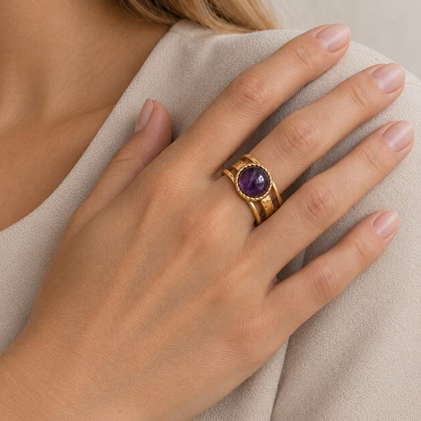 Bague trois anneaux en améthyste portée au doigt, main posée sur l’épaule.