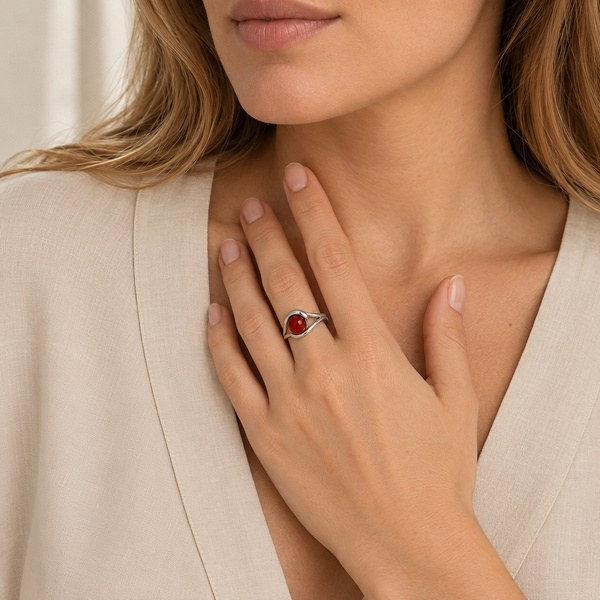 Bague perle en agate rouge portée, la main posée sur la poitrine.