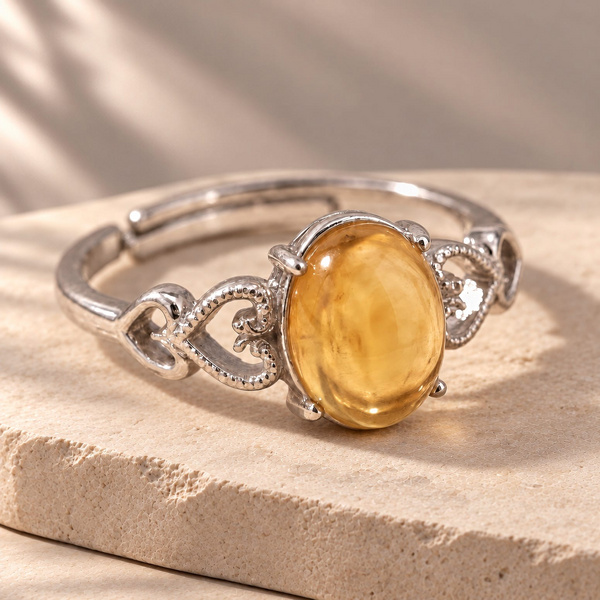 Bague cœurs ajourés en citrine posée de trois quarts, ovale jaune tenu par quatre griffes.