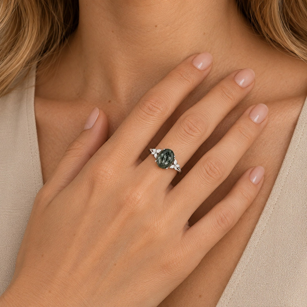 Bague fine en séraphinite portée, la main posée à plat sous le cou.