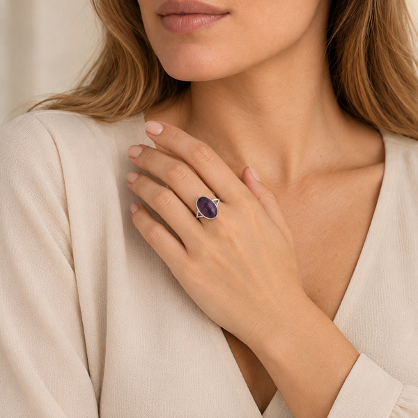 Bague ovale en améthyste portée, la main posée près du cou.