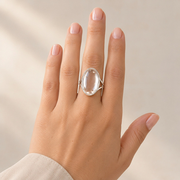 Bague cabochon en cristal de roche portée au doigt, la main ouverte.